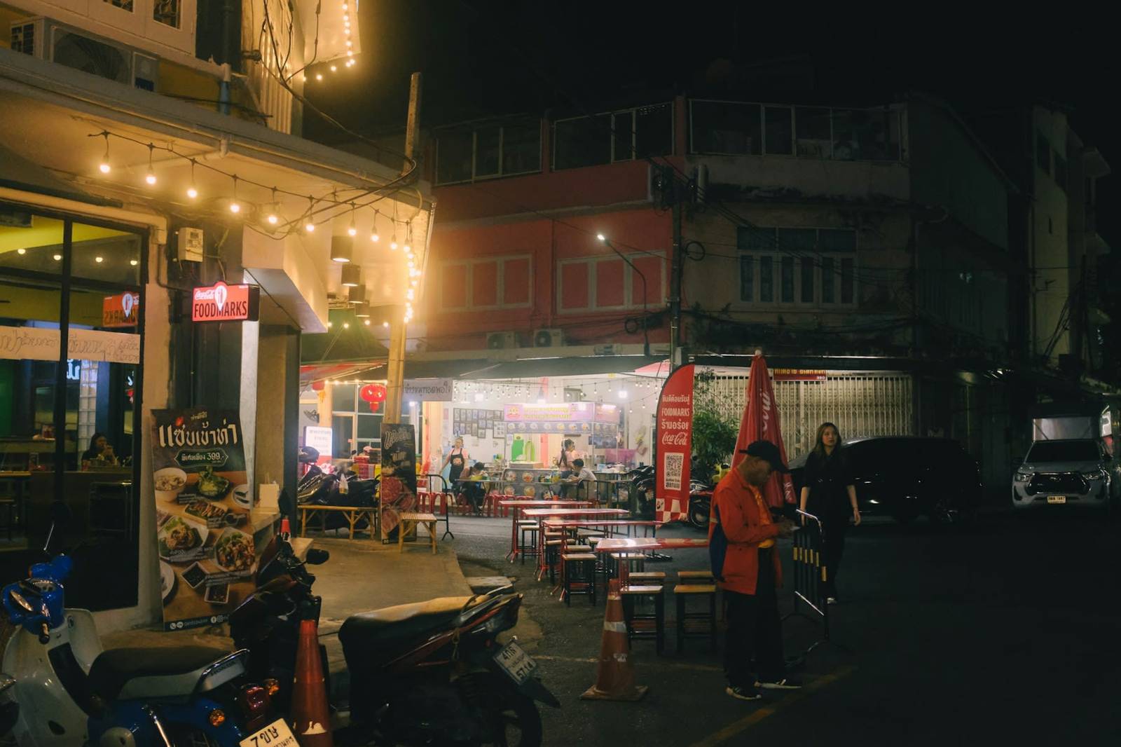 A street of food stalls and plastic stools in the evening in Thailand