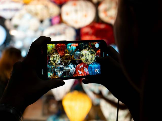 Someone photographing coloured lanterns with a phone