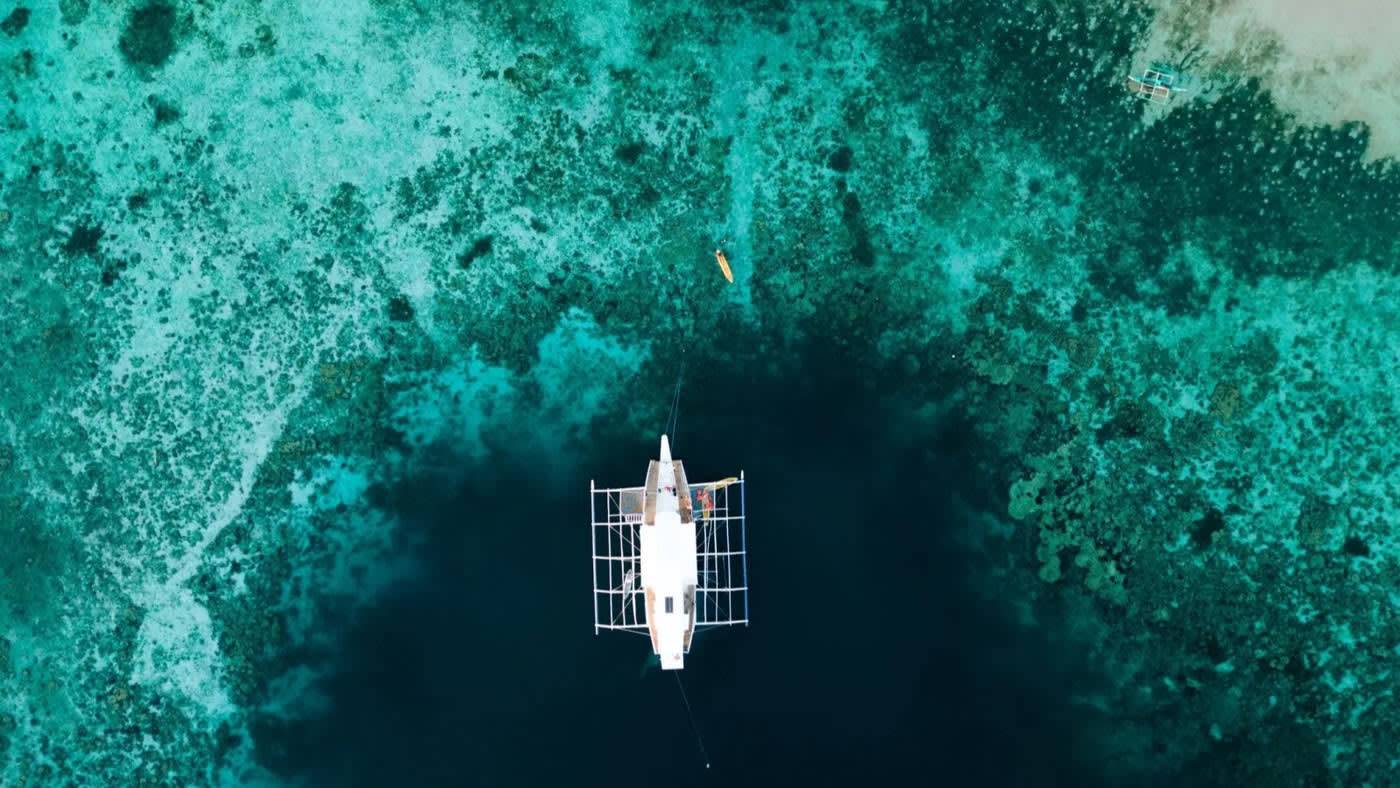 The expedition boat from above, over the coral of Palawan