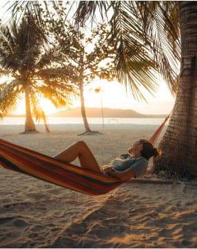 A hammock between the palms at sunset on an island