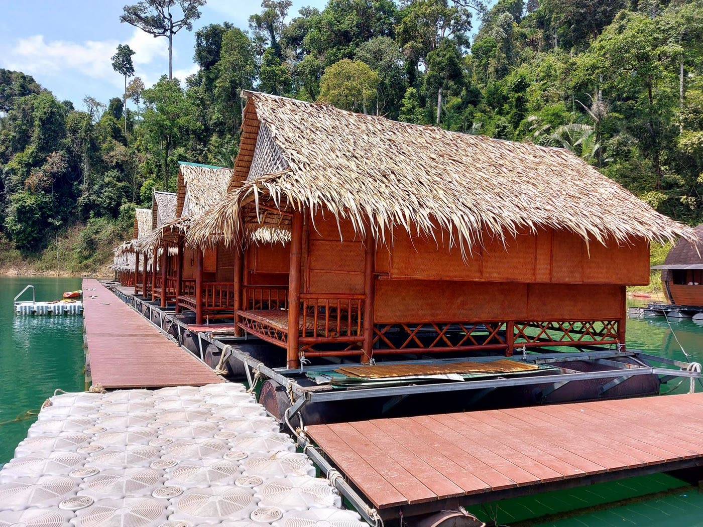 Floating raft houses with thatched roofs along the jetty on Cheow Lan Lake