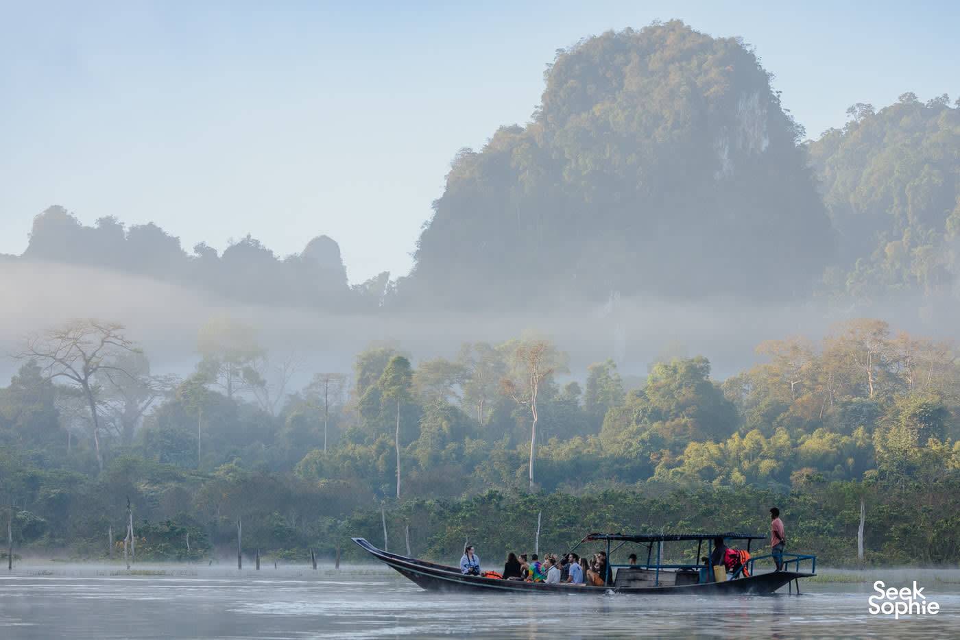Longtail boat in the morning mist above the lake