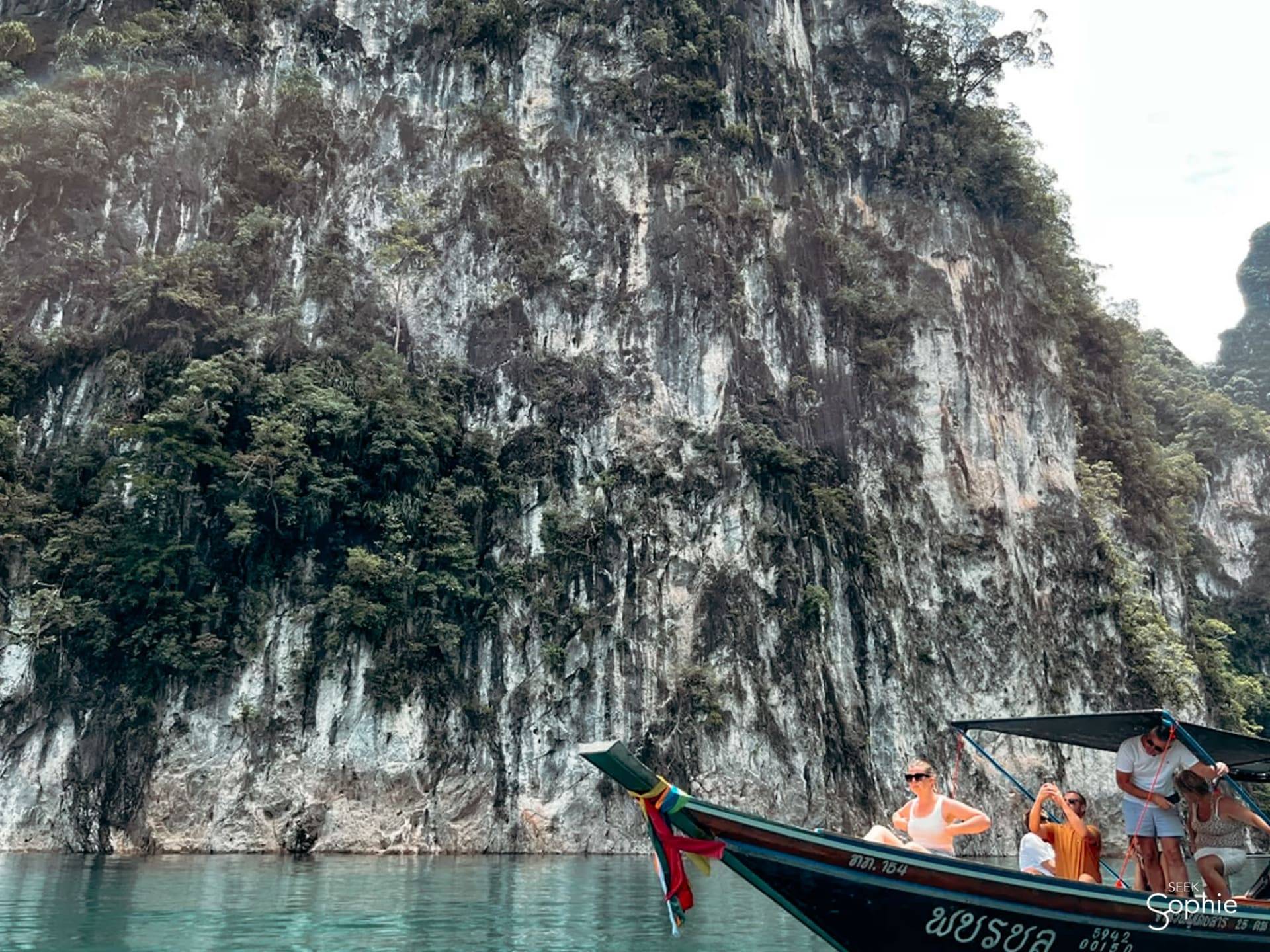 Longtail boat with travellers under the limestone cliffs of Cheow Lan Lake