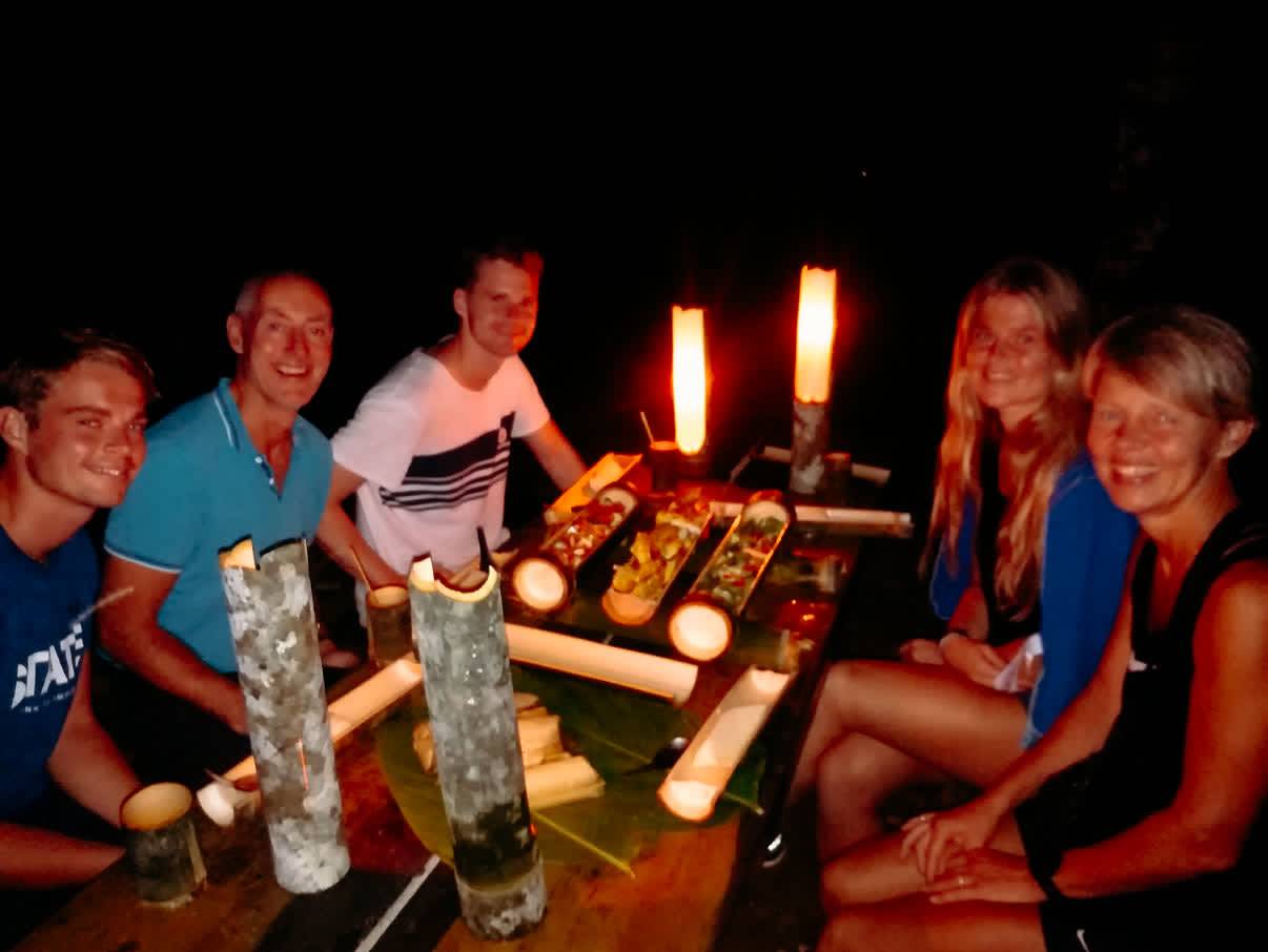 Travellers at a table by candlelight with dinner served from bamboo