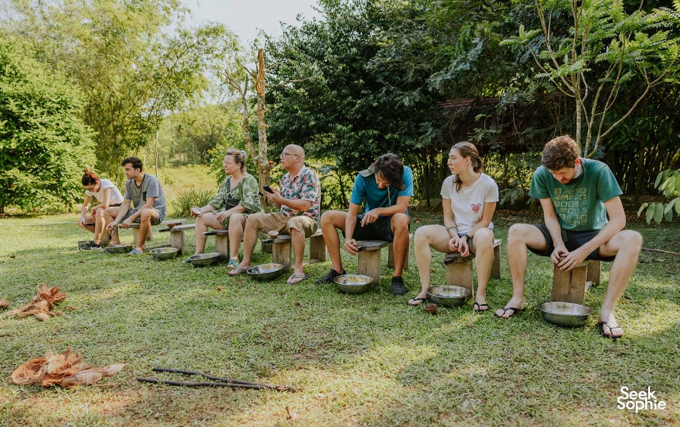 Guests grinding herbs in stone mortars on the grass at the farm