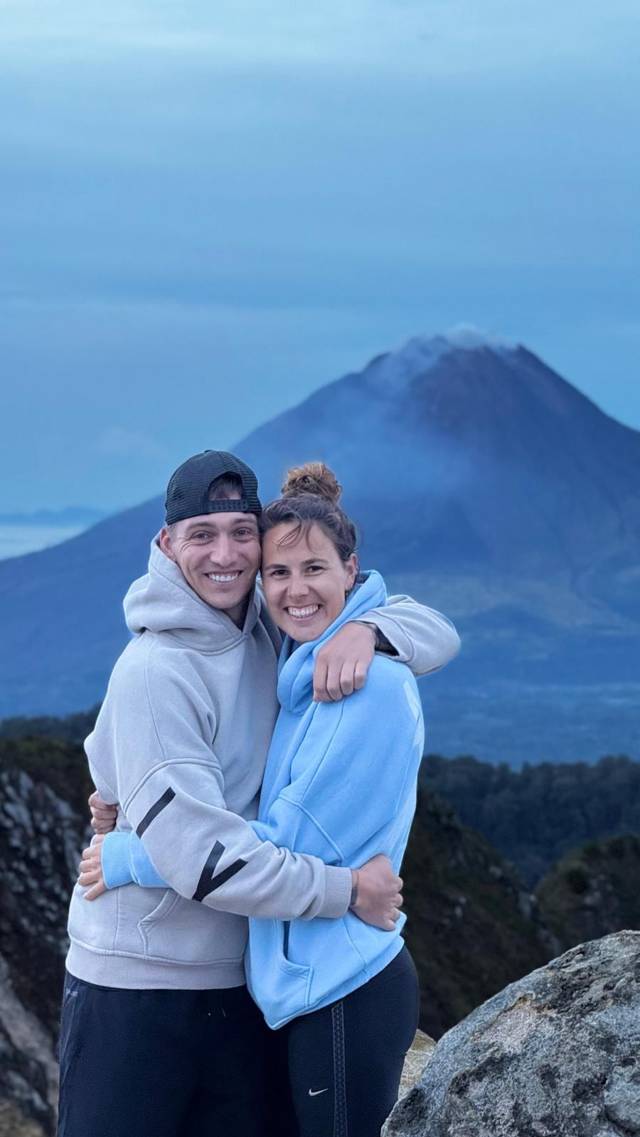 Remco and Anouk hugging and laughing, a volcano in the mist behind them