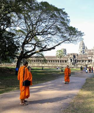 Monks in orange robes walking towards Angkor Wat