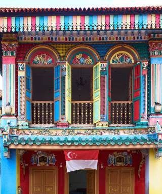 Colourful Peranakan shophouse in Little India with the Singapore flag