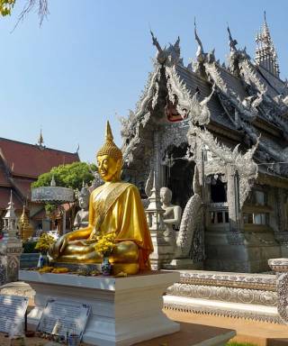 Golden Buddha statue in front of a Thai temple