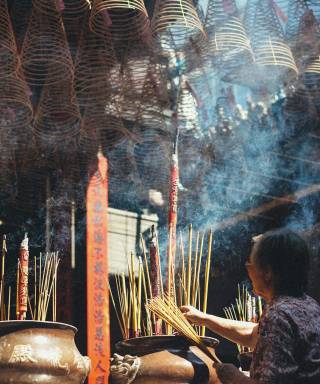 Woman lighting incense sticks in a temple