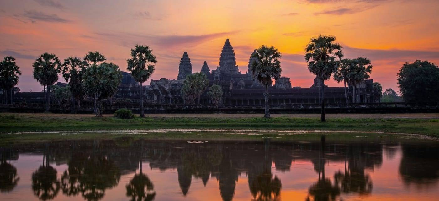The silhouette of Angkor Wat at sunrise, reflected in the water