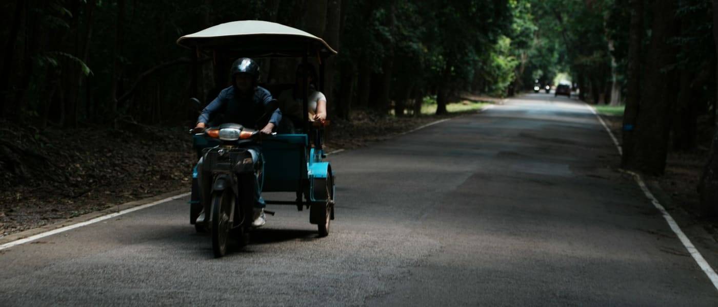 A tuk-tuk on a road through the forest