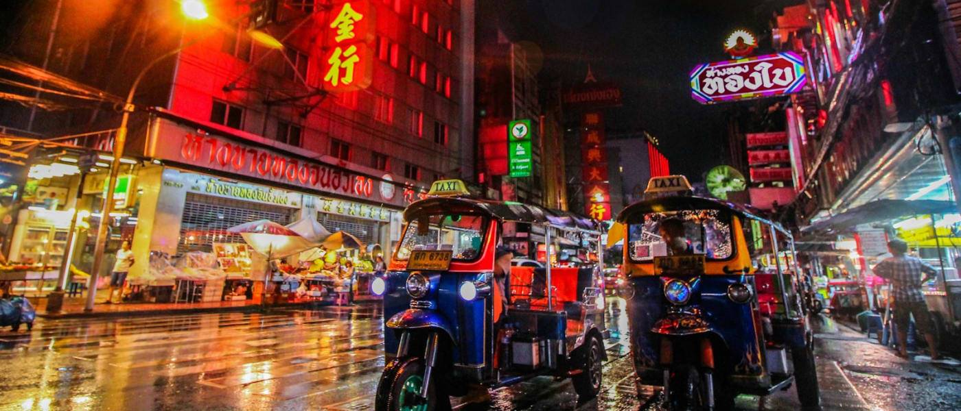 Tuk-tuks in a busy street full of neon signs