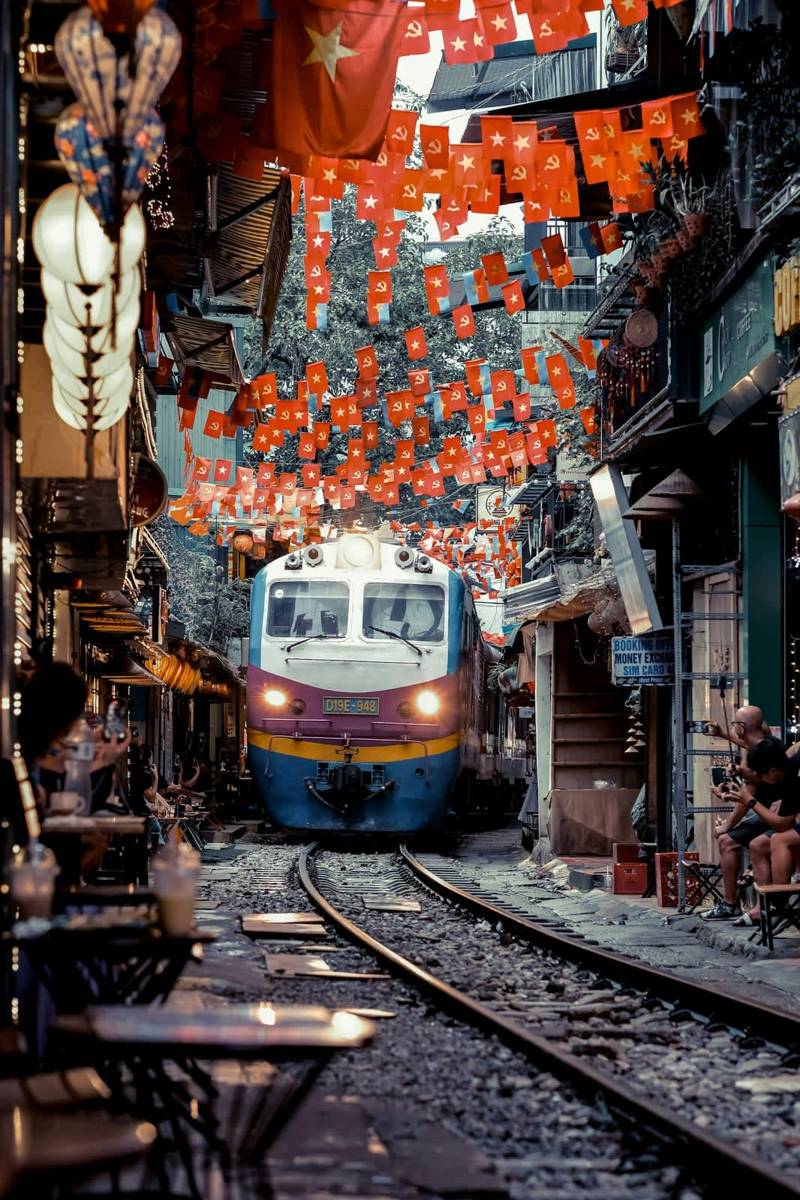 Train squeezing down the narrow Train Street in Hanoi, between the cafés
