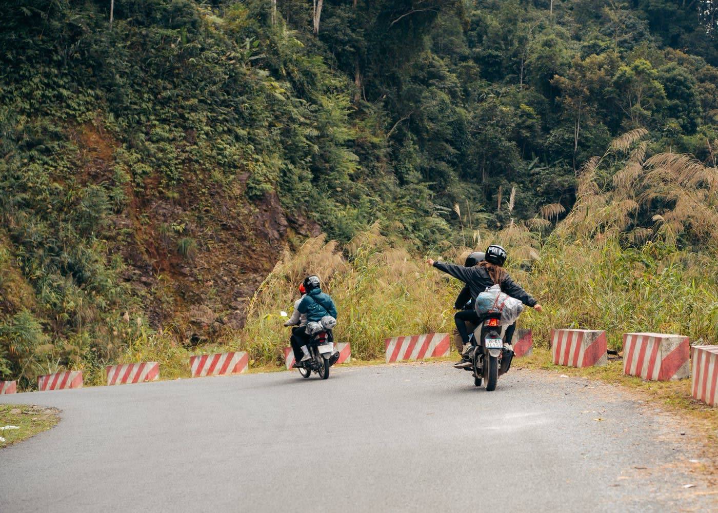 Riders waving on a mountain pass on the Ha Giang Loop