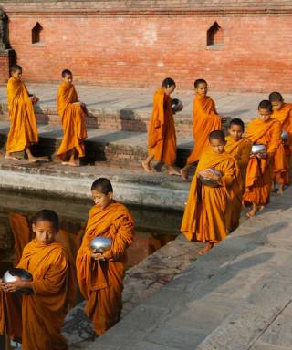Young monks in orange robes walking along the water